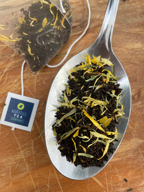 Tea leaves on a spoon with a tea bag and label in the background