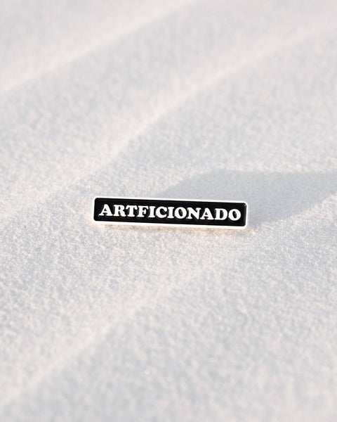 Close-up of a textured white surface with 'ARTIFICIONADO' pin.