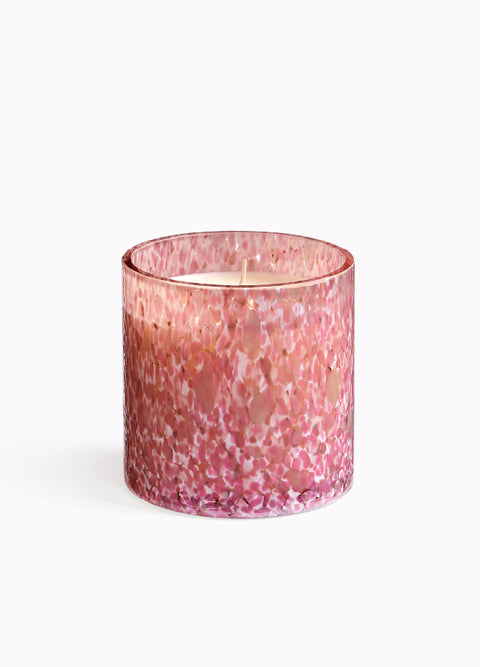 Pink speckled candle in a glass container on a white background