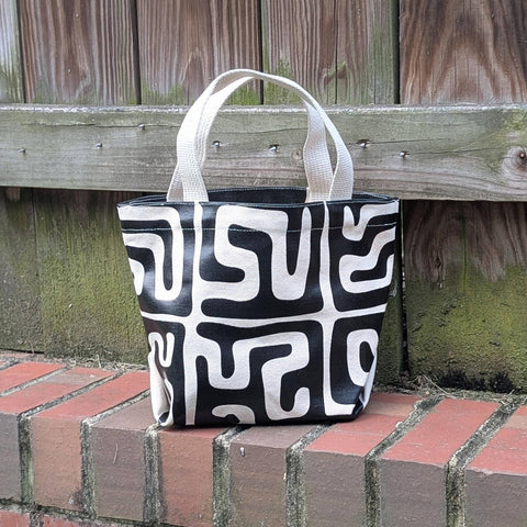 Black and white patterned tote bag on a brick surface with wooden background