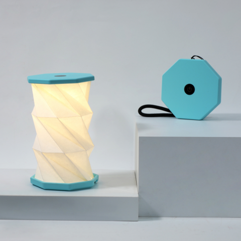 Foldable lamp with turquoise top and base on a gray background