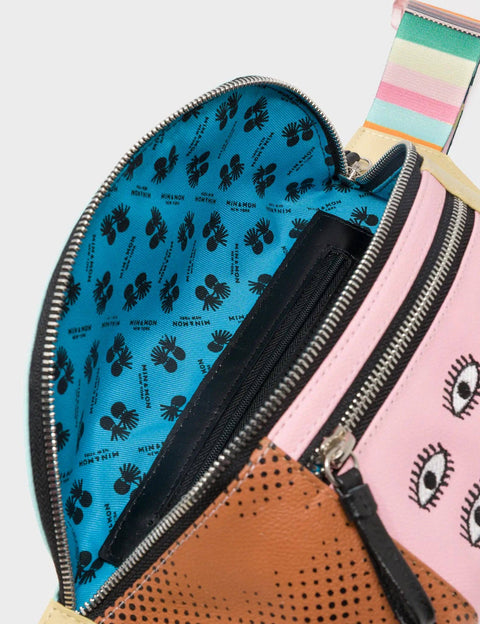 Open waist bag with blue interior featuring black pattern, pink exterior with eye pattern, and brown exterior.