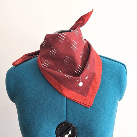 Red bandana with white patterns on a blue mannequin torso against a white background