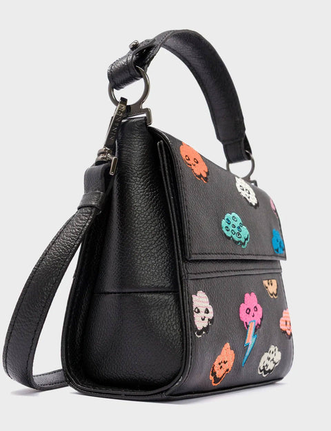 Black handbag with colorful cloud-themed patches on a light gray background