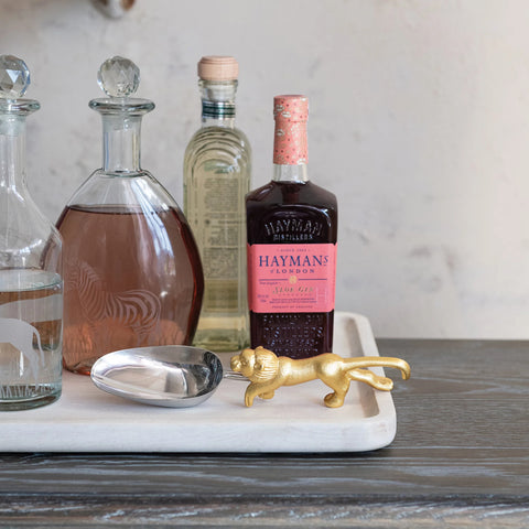 Bottles of alcohol and glass with a scoop with lion shaped handle on a marble tray with decorative items