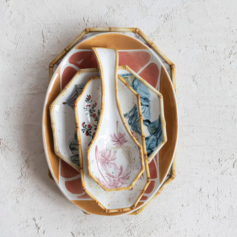 Decorative ceramic plates and spoon with artistic design on a light gray background