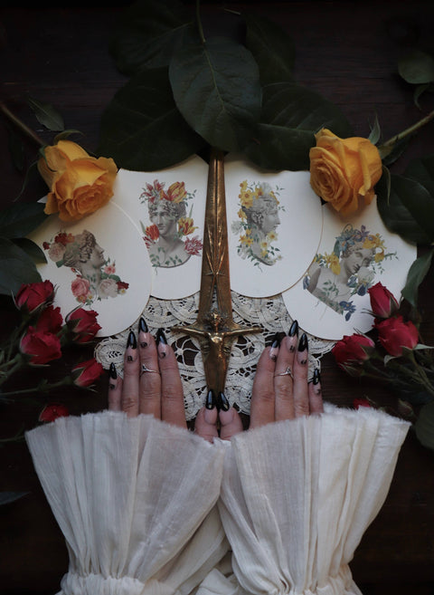Hands with note cards, a dagger, and surrounded by yellow and red roses.