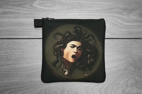 Black pouch with Medusa design on a wooden surface
