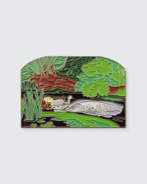 Enamel pin with a nature scene design on a white background