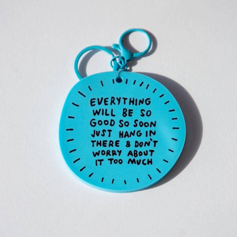 Blue keychain with motivational quote on a light gray background