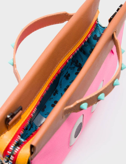Close-up of a pink sandal with tan straps and blue interior on a light gray background